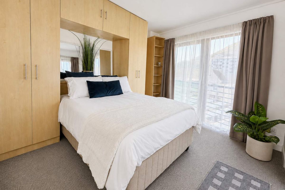 A well-maintained bedroom featuring extensive built-in cabinetry, integrated shelving, and a large sliding glass door providing natural light and access to the exterior.