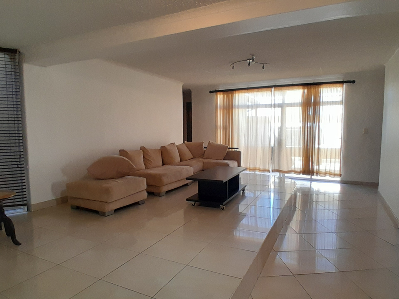 Spacious living room featuring large format floor tiles, a raised platform area, and sliding glass doors providing access to the exterior.