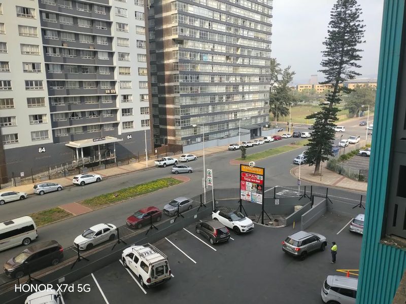 An elevated view overlooking a street intersection, parking area, and surrounding high-rise apartment buildings.