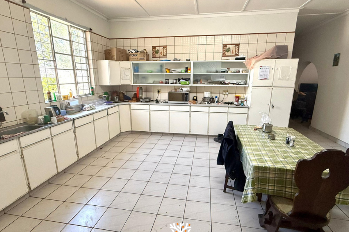 Spacious kitchen featuring extensive white cabinetry, tiled walls, and large windows, offering a functional layout with ample storage and preparation space.