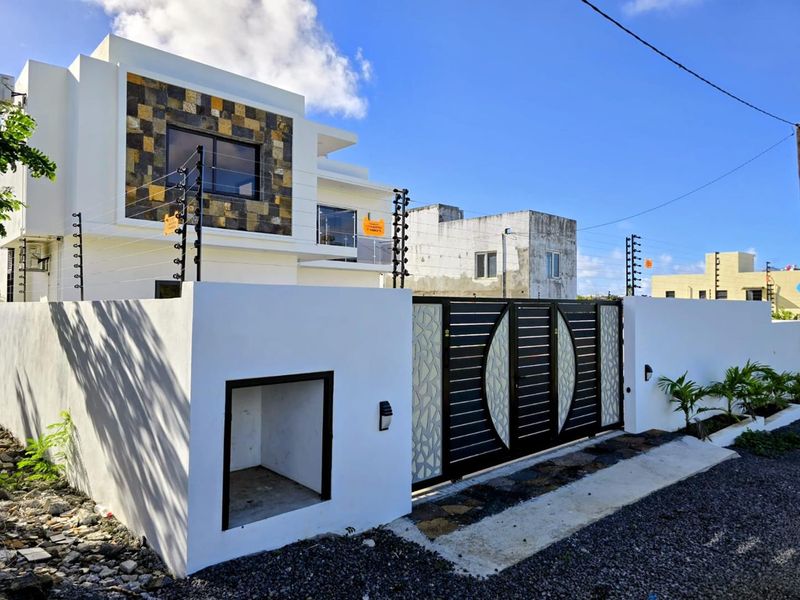 Modern residential property exterior featuring a secure perimeter wall, decorative metal gate, and integrated electric fencing for enhanced security.