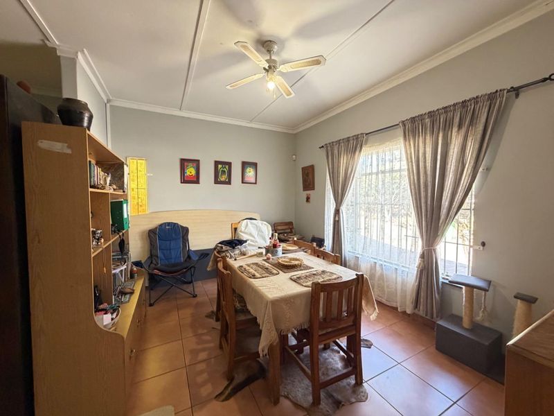 A functional dining room featuring tiled flooring, a ceiling fan, and natural light through a large window.