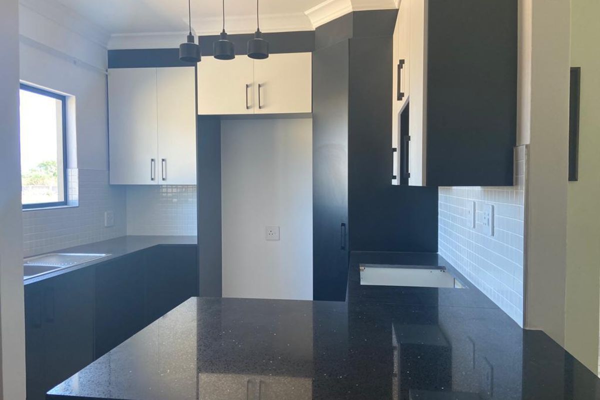 Modern kitchen featuring high-contrast black and white cabinetry, stone countertops, subway tile backsplash, and pendant lighting, ready for appliance installation.