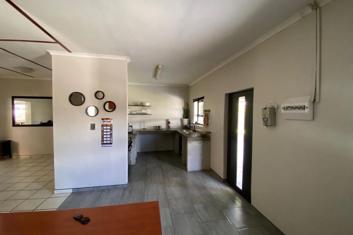 A functional kitchen area featuring concrete countertops, tiled flooring, and an exposed electrical distribution board, offering potential for modern renovation and aesthetic improvement.