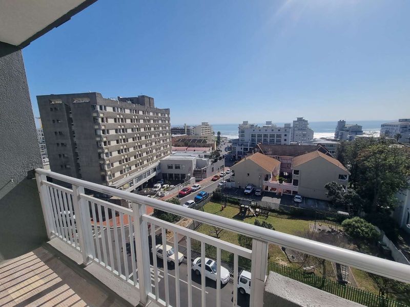 A balcony with a metal balustrade offering an elevated urban and coastal view.
