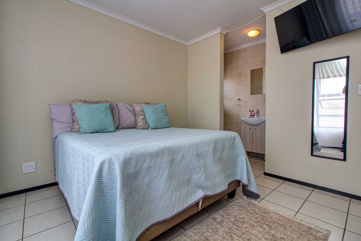 A bedroom featuring tiled flooring and an en-suite bathroom with a vanity basin.