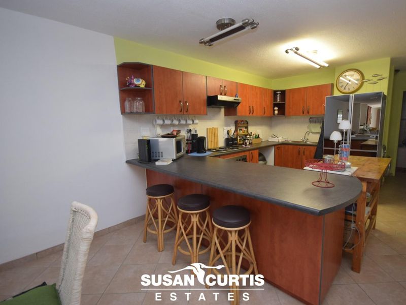 A functional kitchen featuring wood-tone cabinetry, a breakfast bar, and tiled flooring, offering a practical layout for daily meal preparation.