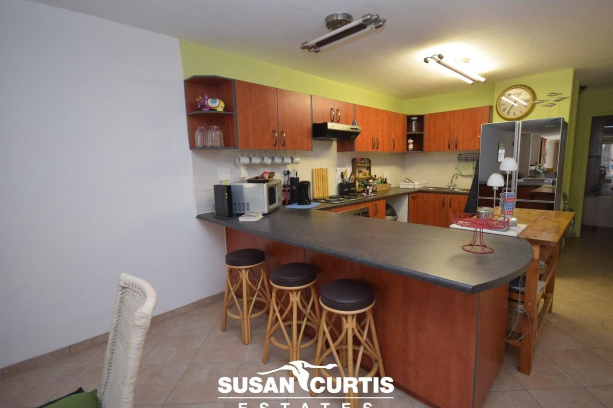 A functional kitchen featuring wood-tone cabinetry, a breakfast bar, and tiled flooring, offering a practical layout for daily meal preparation.