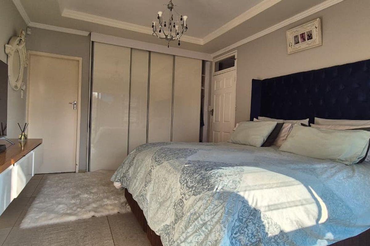 A well-maintained bedroom featuring built-in sliding door wardrobes, tiled flooring, and decorative ceiling coving.