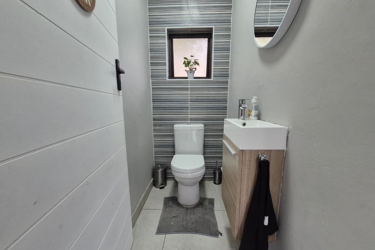 A compact, modern guest bathroom featuring a wall-mounted vanity, contemporary basin, and stylish horizontal-striped feature wall tiling.