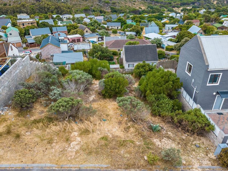 Aerial view of a vacant residential plot situated in a developed neighborhood, featuring established vegetation and boundary retaining walls.