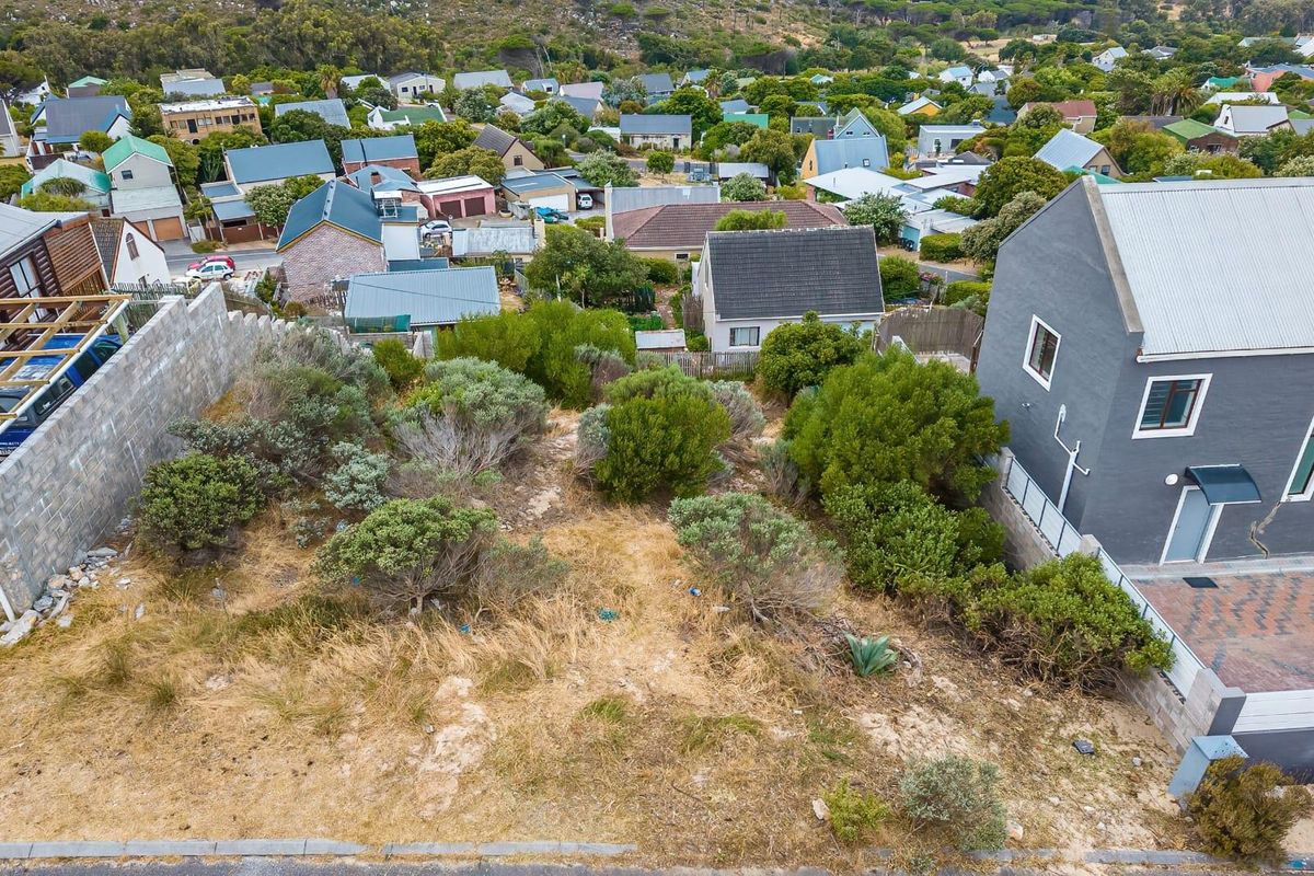 Aerial view of a vacant residential plot situated in a developed neighborhood, featuring established vegetation and boundary retaining walls.