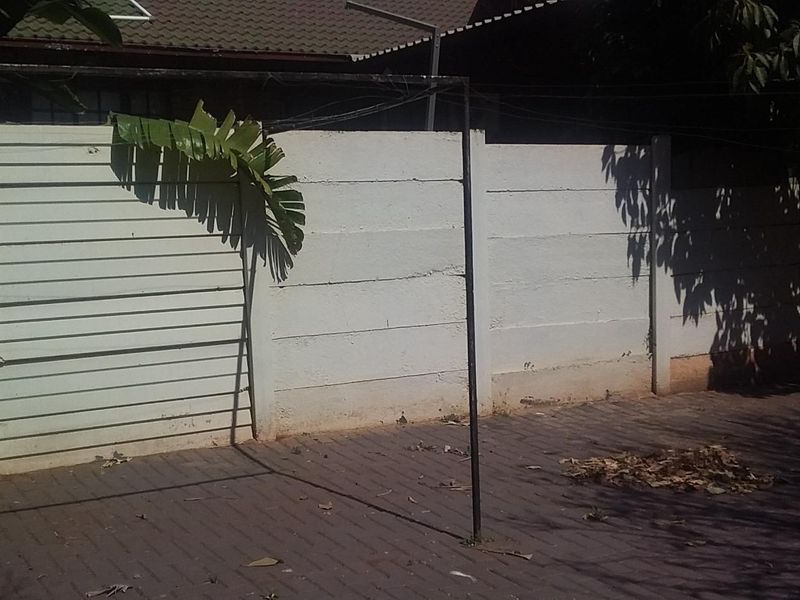 A rear courtyard area featuring a precast concrete boundary wall and paved flooring with a fixed metal washing line structure.