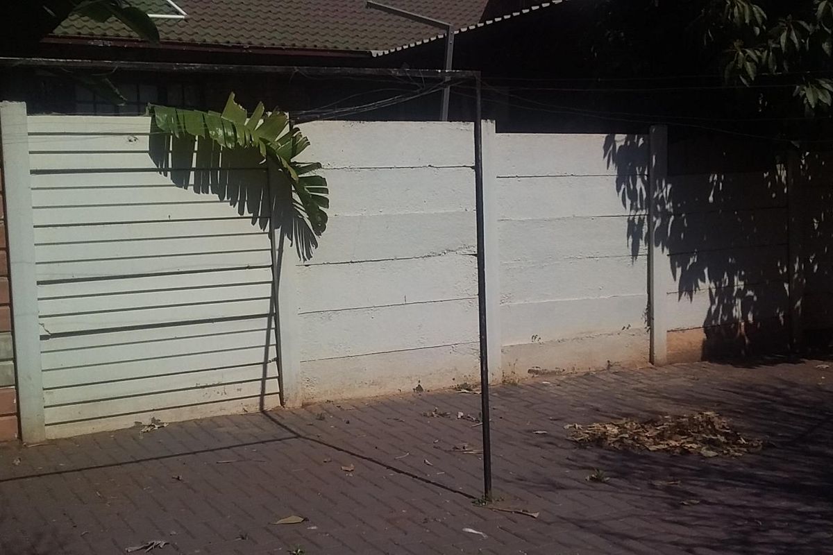 A rear courtyard area featuring a precast concrete boundary wall and paved flooring with a fixed metal washing line structure.