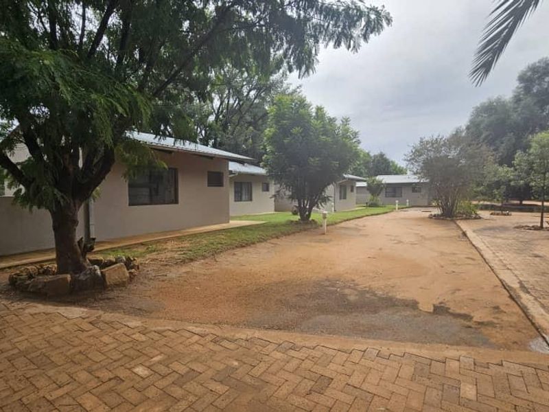 Exterior view of a mixed-use property featuring multiple units with paved driveway access and established trees.