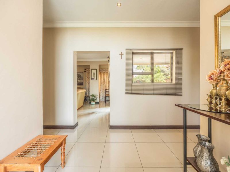 A bright and welcoming entrance hall featuring neutral tiled flooring, clean wall finishes, and a view through to the adjoining living area.