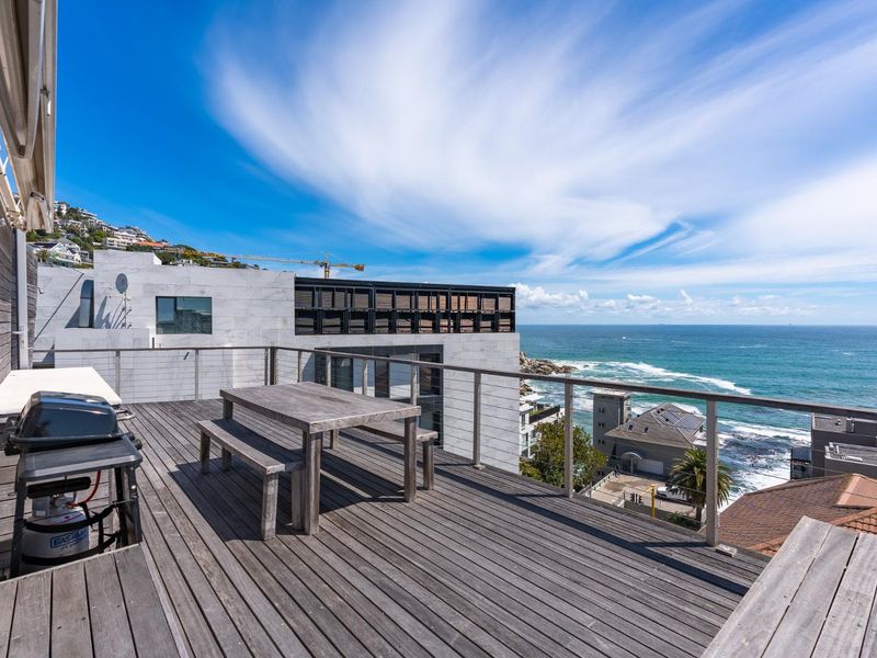 Spacious outdoor balcony featuring timber decking and a modern glass balustrade, offering expansive ocean views and a perfect setting for outdoor entertaining.