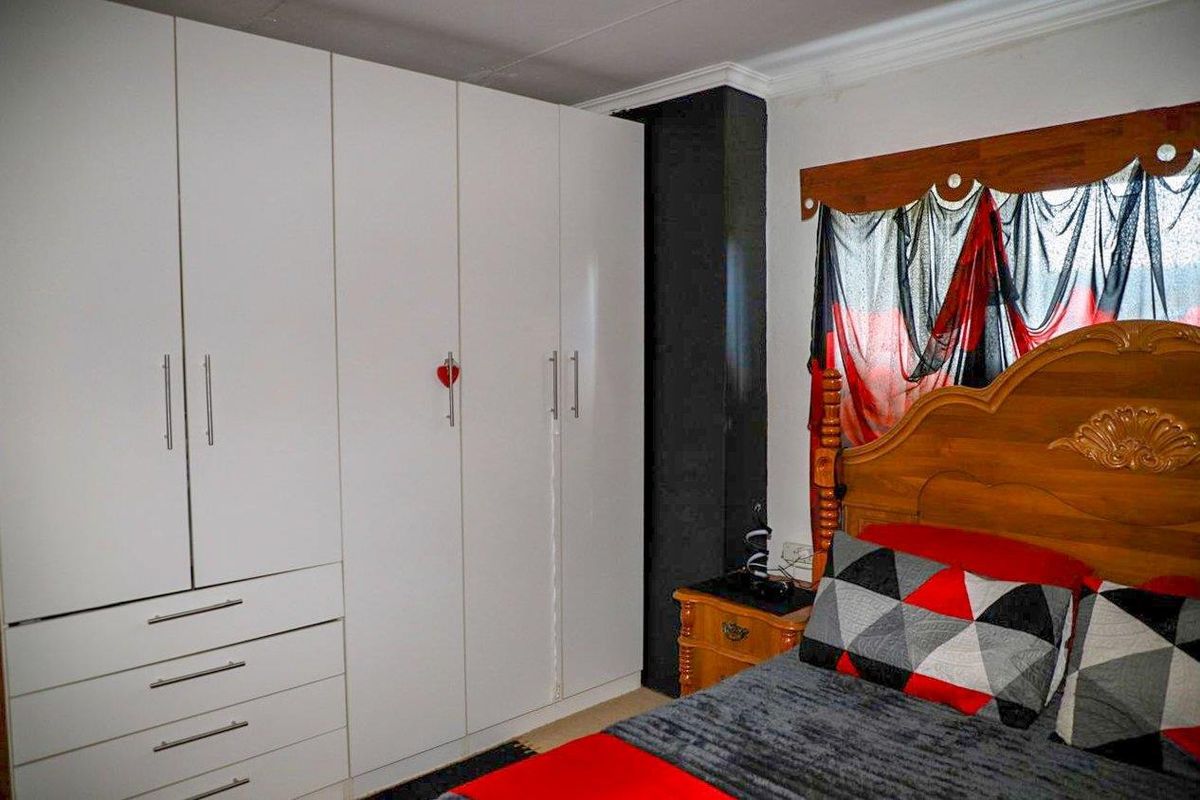 A bedroom featuring built-in white cabinetry with integrated drawers and a dark accent pillar, providing ample storage space.