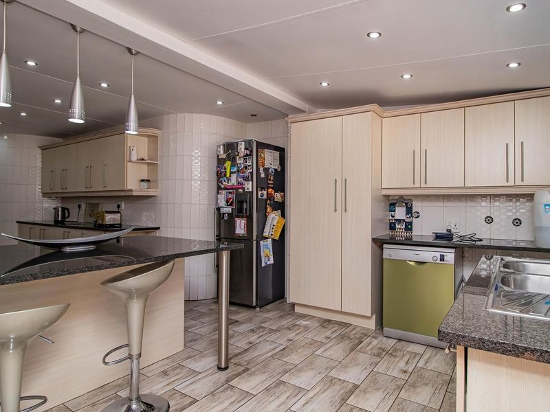 A functional kitchen featuring granite countertops, ample laminate cabinetry, a double bowl stainless steel sink, and modern recessed lighting throughout the space.