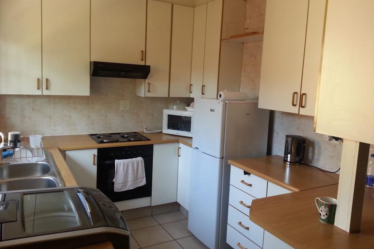 A functional kitchen featuring laminate countertops, built-in oven, electric hob, extractor fan, and ample upper and lower cabinetry storage.