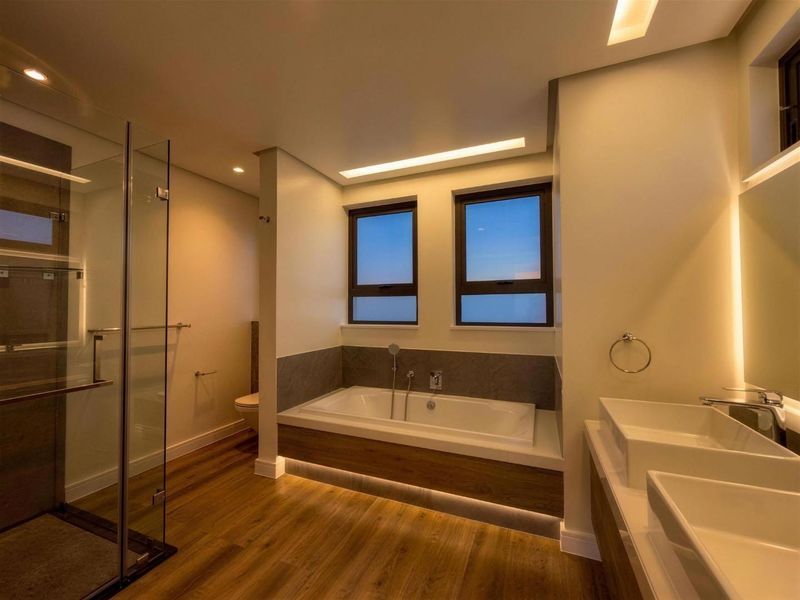 Modern, well-lit bathroom featuring a glass-enclosed shower, a built-in bathtub, and a double vanity with contemporary finishes.