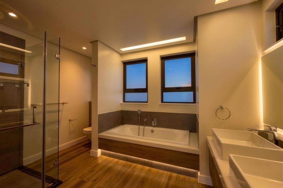 Modern, well-lit bathroom featuring a glass-enclosed shower, a built-in bathtub, and a double vanity with contemporary finishes.
