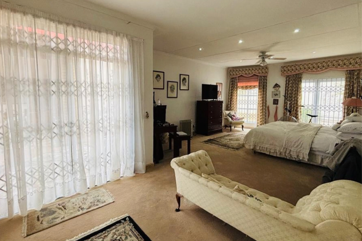 Spacious bedroom featuring recessed lighting, a ceiling fan, and large sliding glass doors with security gates providing access to the exterior.