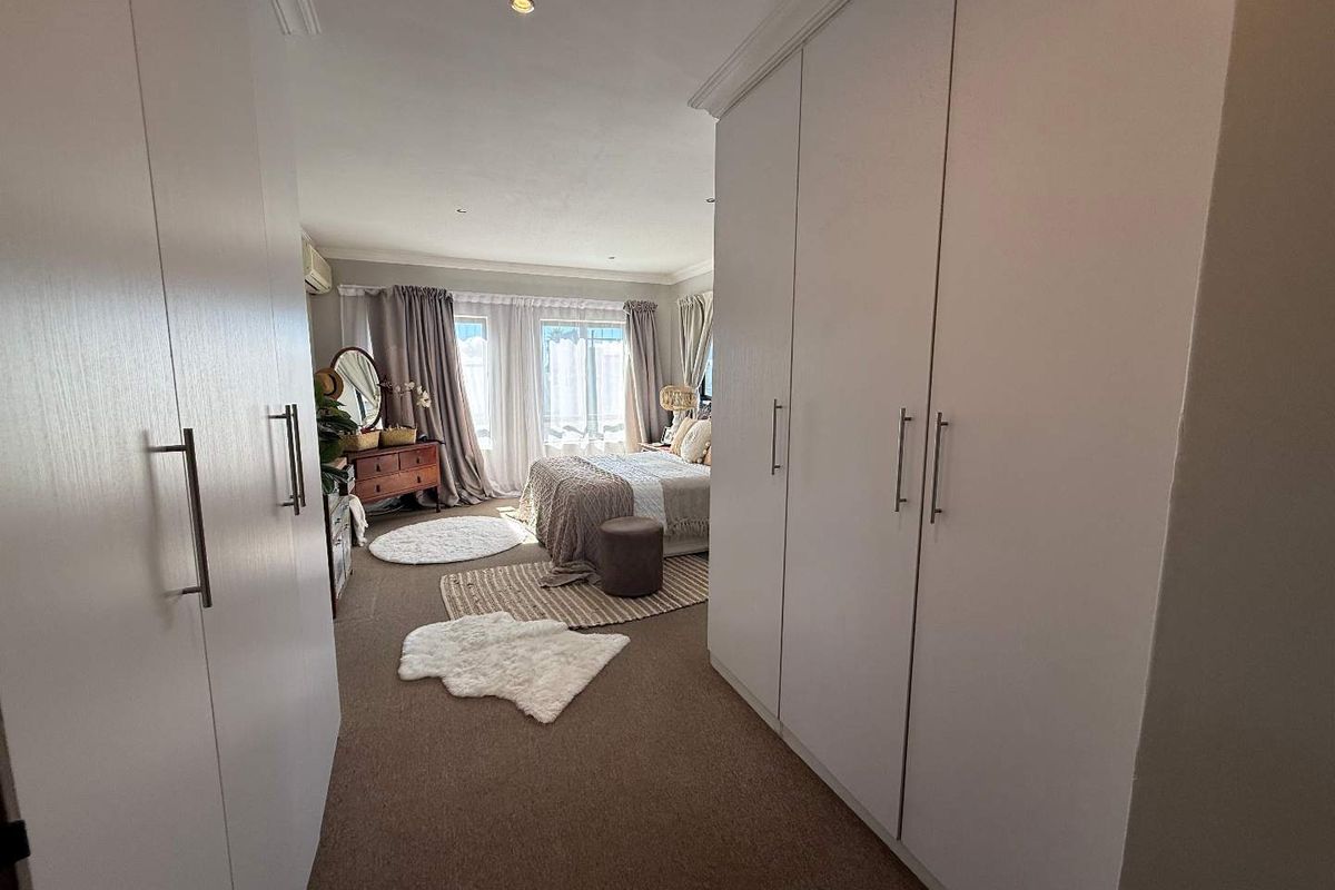 A spacious bedroom featuring extensive built-in cabinetry, neutral carpeting, and natural light flowing through large windows.