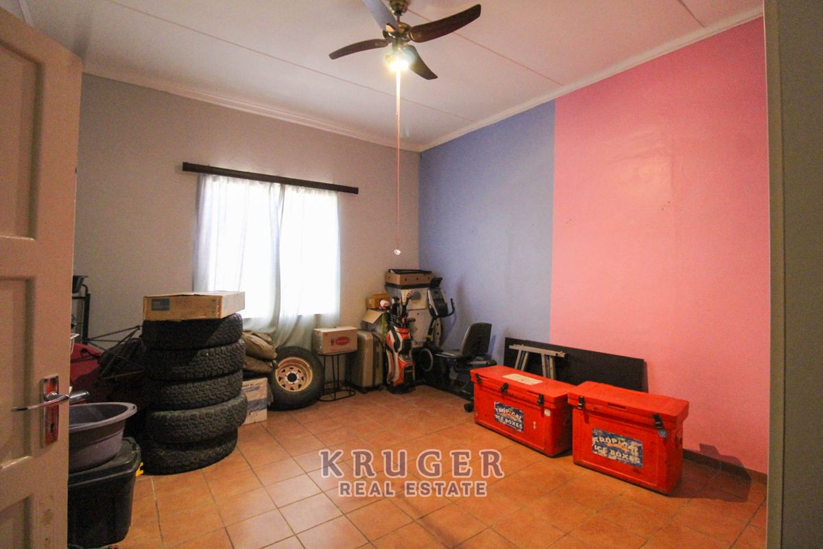 A bedroom featuring tiled flooring and a ceiling fan, currently utilized as storage space.