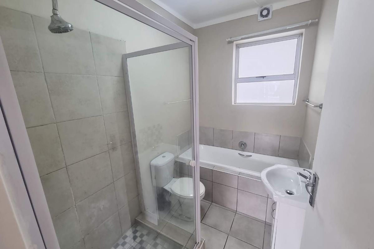 A functional bathroom featuring a separate shower enclosure, bathtub, pedestal basin, and tiled finishes throughout.