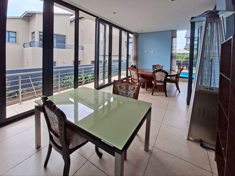 Spacious open-plan living and dining area featuring large format floor tiles and expansive aluminium stacker doors opening to an outdoor patio.