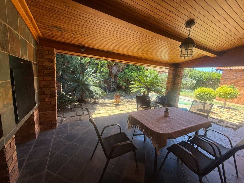 Covered patio featuring a built-in braai, timber-clad ceiling, and slate flooring, overlooking a private garden area.