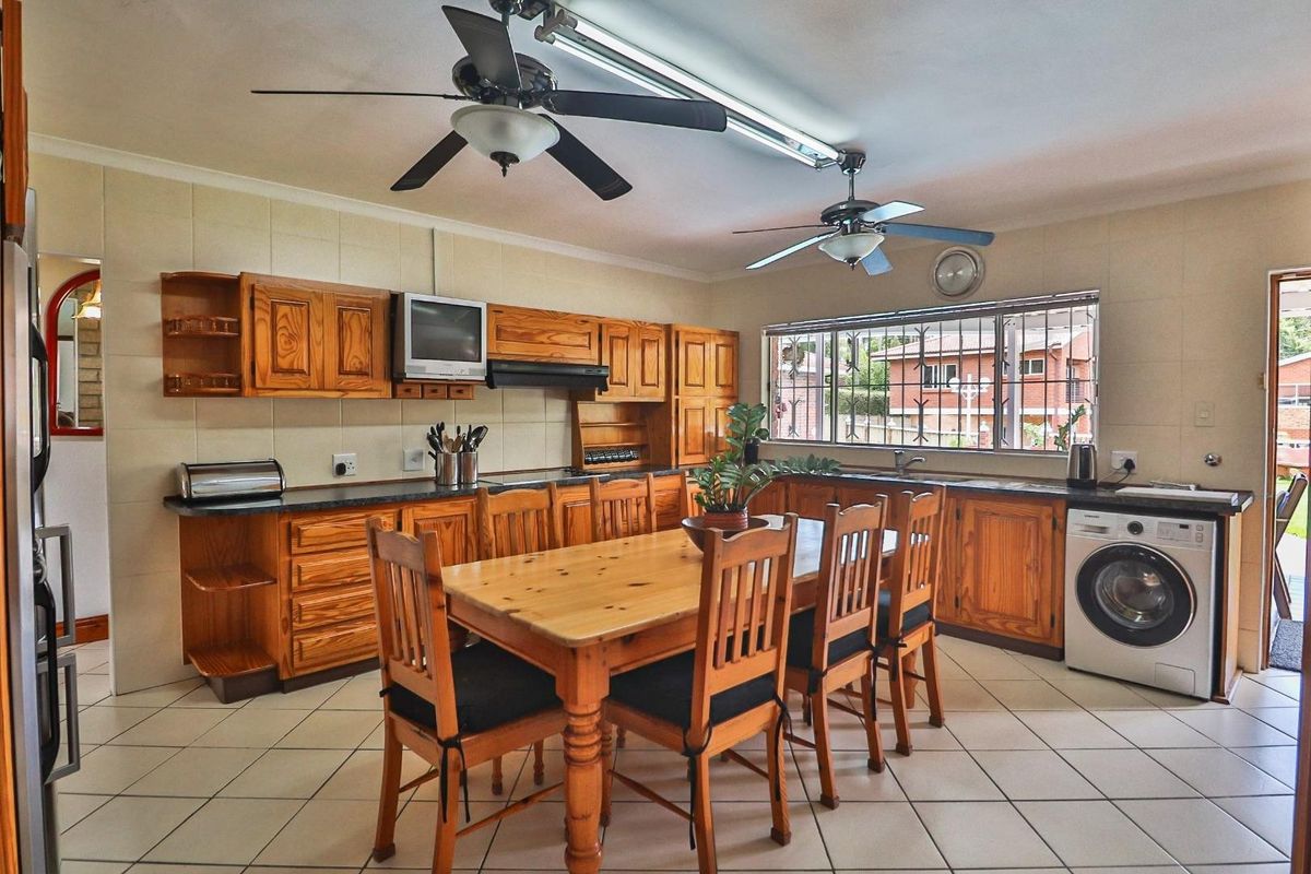 Spacious kitchen featuring traditional wooden cabinetry, tiled flooring, and integrated appliances, offering a functional layout with ample counter space and natural light.