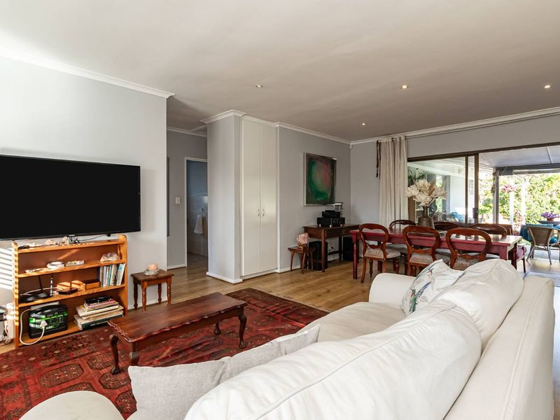 Spacious open-plan living and dining area featuring laminate flooring, recessed lighting, and large sliding doors providing seamless access to the outdoor patio.