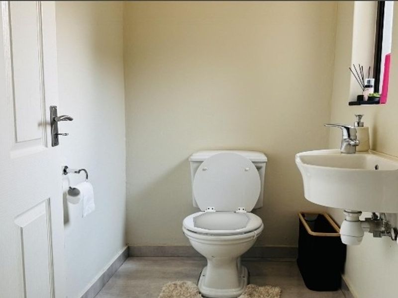 A compact guest bathroom featuring a white toilet and a wall-mounted basin with modern fixtures.