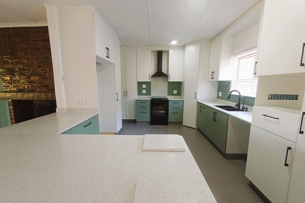 Modern kitchen featuring white and sage green cabinetry, quartz countertops, a built-in stove with extractor fan, and a sleek tiled backsplash.