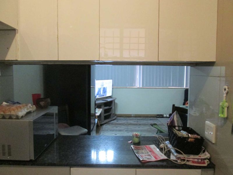 A kitchen area featuring built-in cabinetry and a dark granite countertop, with a pass-through window looking into the adjacent living space.