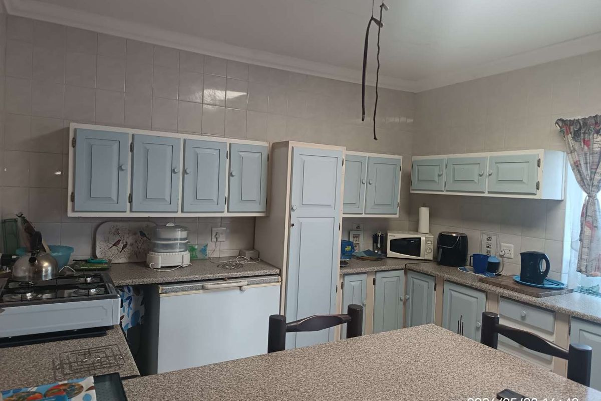 A functional kitchen featuring light blue cabinetry, stone-look laminate countertops, and tiled splashbacks, offering a practical layout for daily meal preparation.