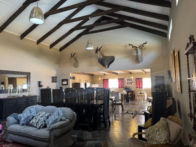 Spacious open-plan living and dining area featuring high vaulted ceilings with exposed timber trusses and durable tiled flooring.