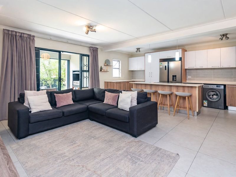 Spacious open-plan living area featuring a modern kitchen with island, tiled floors, and sliding doors leading to an outdoor patio space.