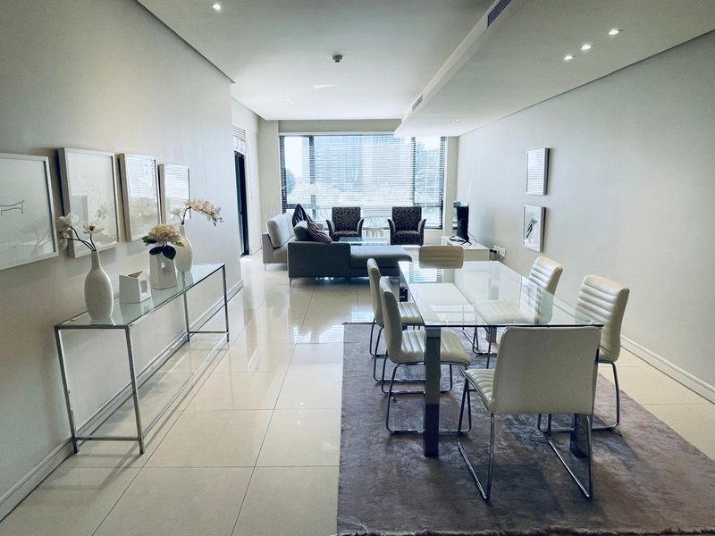 Spacious open-plan living and dining area featuring large format floor tiles, recessed lighting, and ducted air conditioning with abundant natural light.