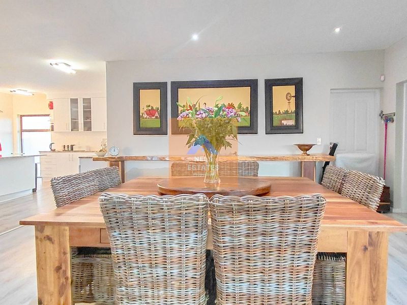 An open-plan dining and kitchen area featuring modern laminate flooring, recessed lighting, and a functional kitchen layout with built-in appliances.