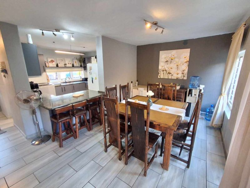 Open plan kitchen and dining area featuring a granite breakfast bar, modern cabinetry, and tiled flooring throughout the living space.