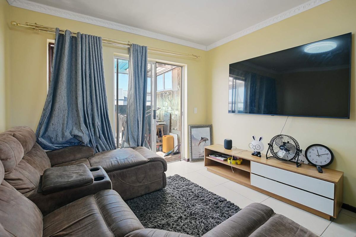 A comfortable living room featuring tiled flooring, crown molding, and a sliding glass door providing access to an outdoor balcony area.
