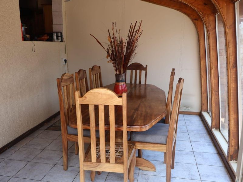 Dining area featuring tiled flooring and a distinctive timber arched window frame, providing a functional space with potential for cosmetic updates.
