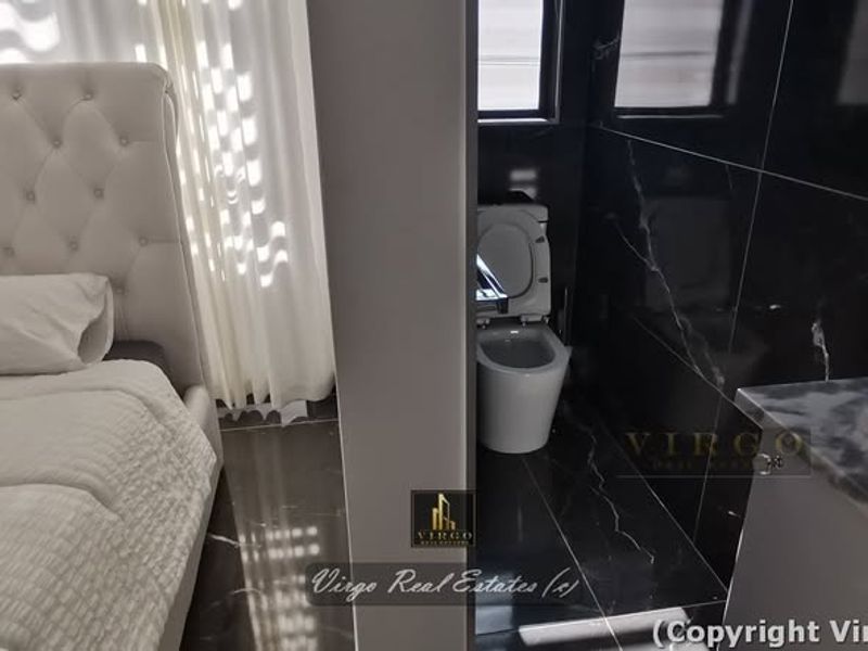 A modern bedroom featuring an open-plan en-suite bathroom with sleek black marble-effect tiling, a wall-mounted toilet, and a contemporary vanity basin.