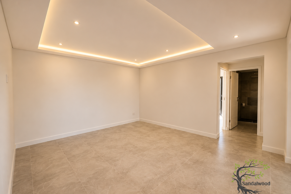 A bright, modern bedroom featuring neutral tiled flooring, recessed ceiling lighting, and an adjoining en-suite bathroom.