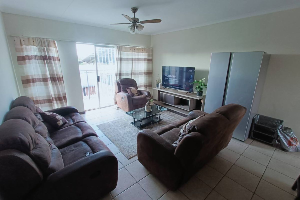A living room featuring tiled flooring, a ceiling fan, and sliding glass doors that provide access to an outdoor balcony area.