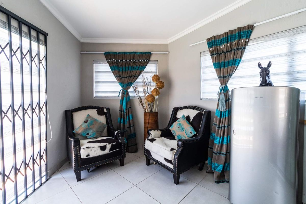 A bright living area featuring tiled flooring, neutral wall finishes, and a security gate on the glass door.