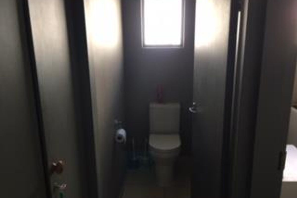 A compact, private bathroom featuring a modern toilet suite and a small window for natural light.